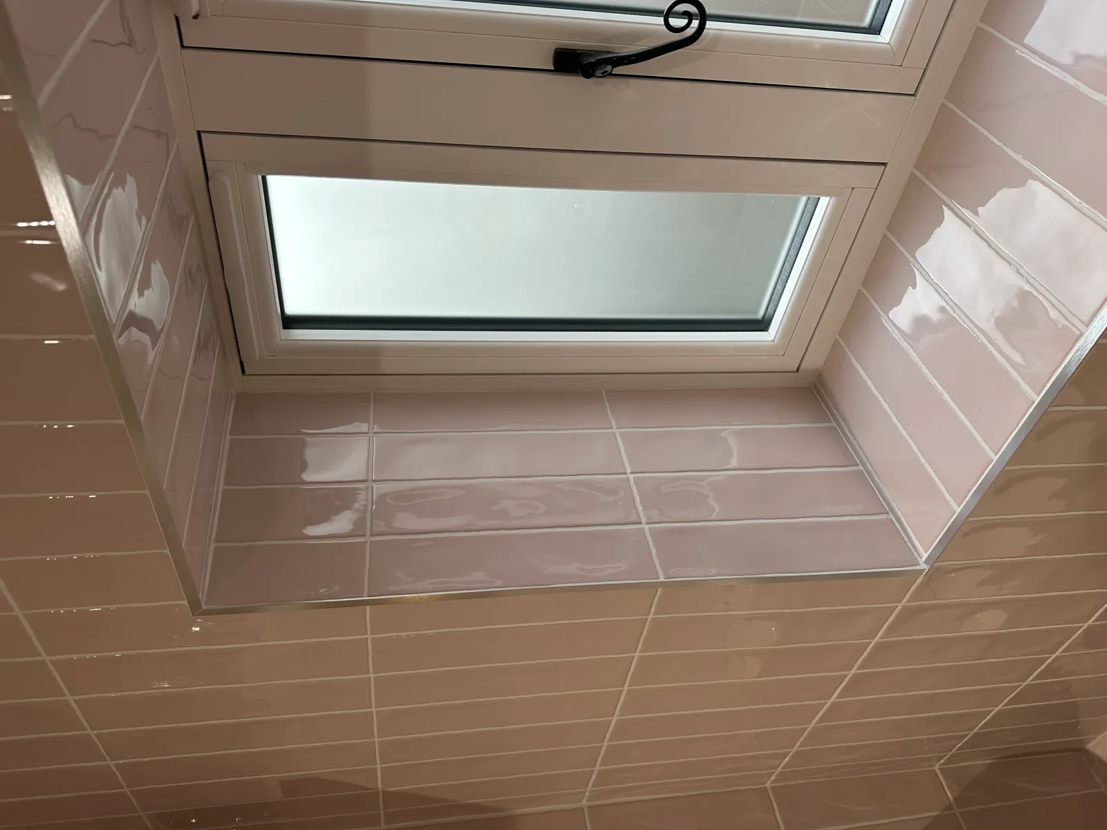 Pink gloss metro tiling with chrome trim around a window
