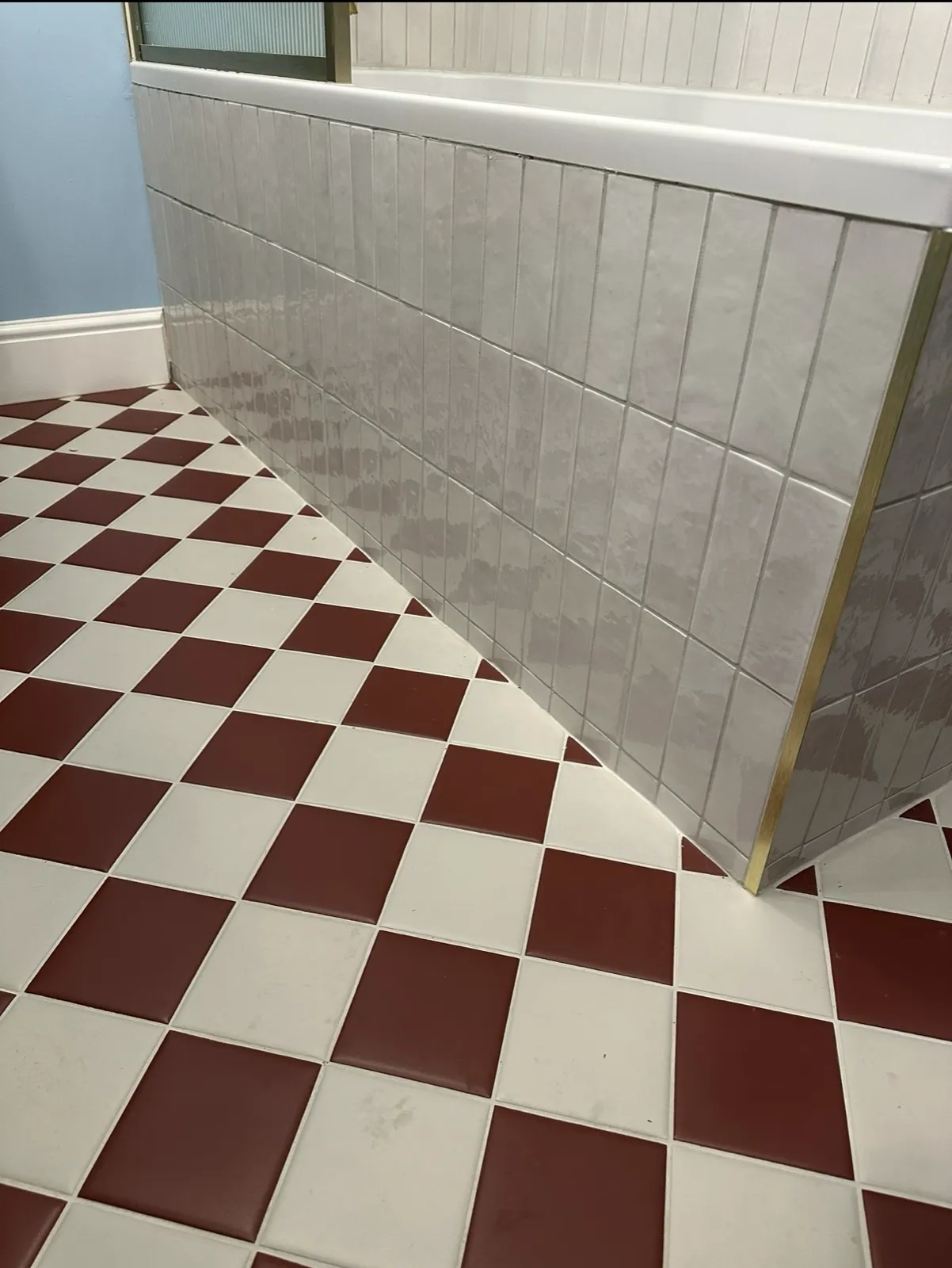 Red and white checkerboard bathroom floor with brass edge trim